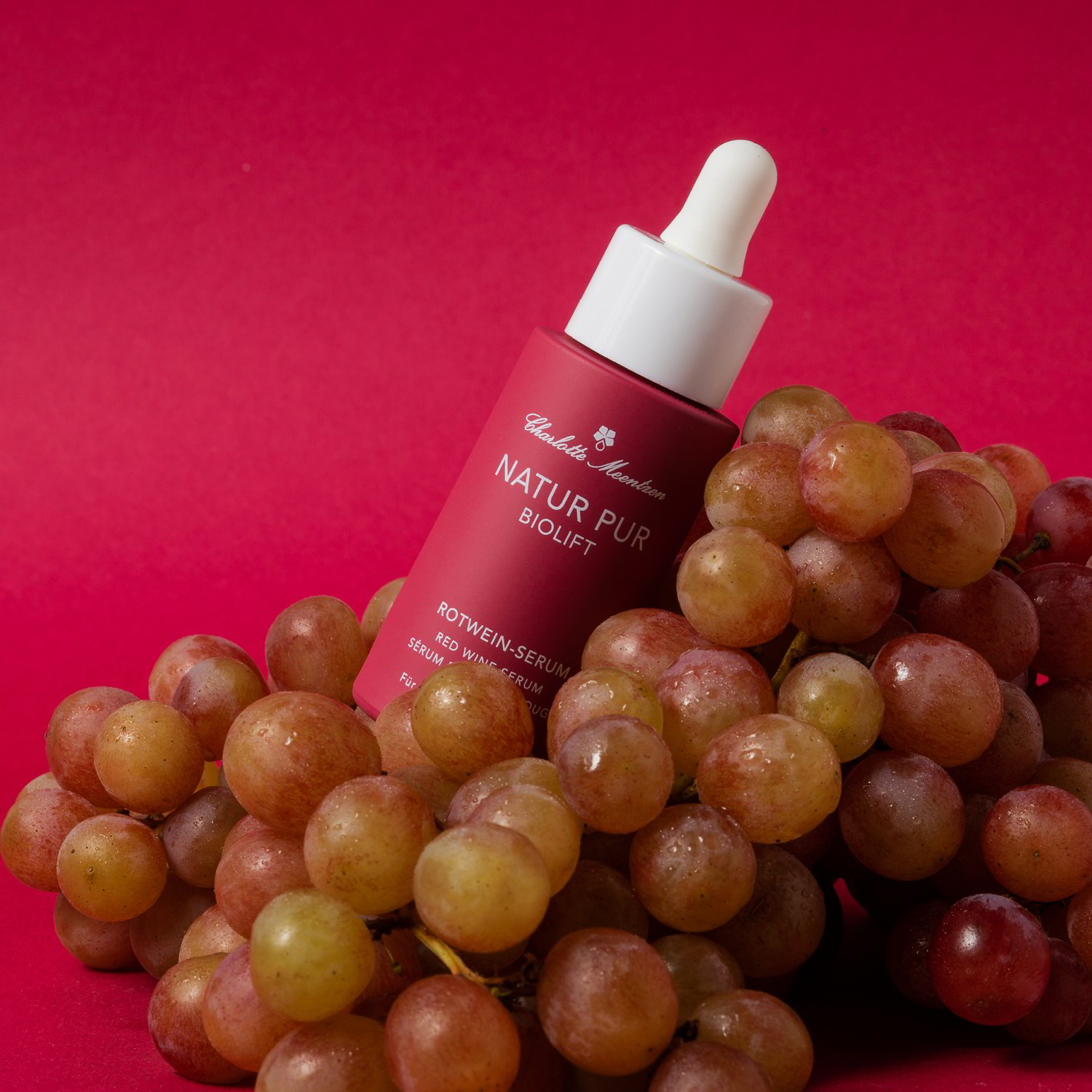 Natur Pur BIOLIFT Rotwein-Serum auf Weintrauben vor rotem Hintergund